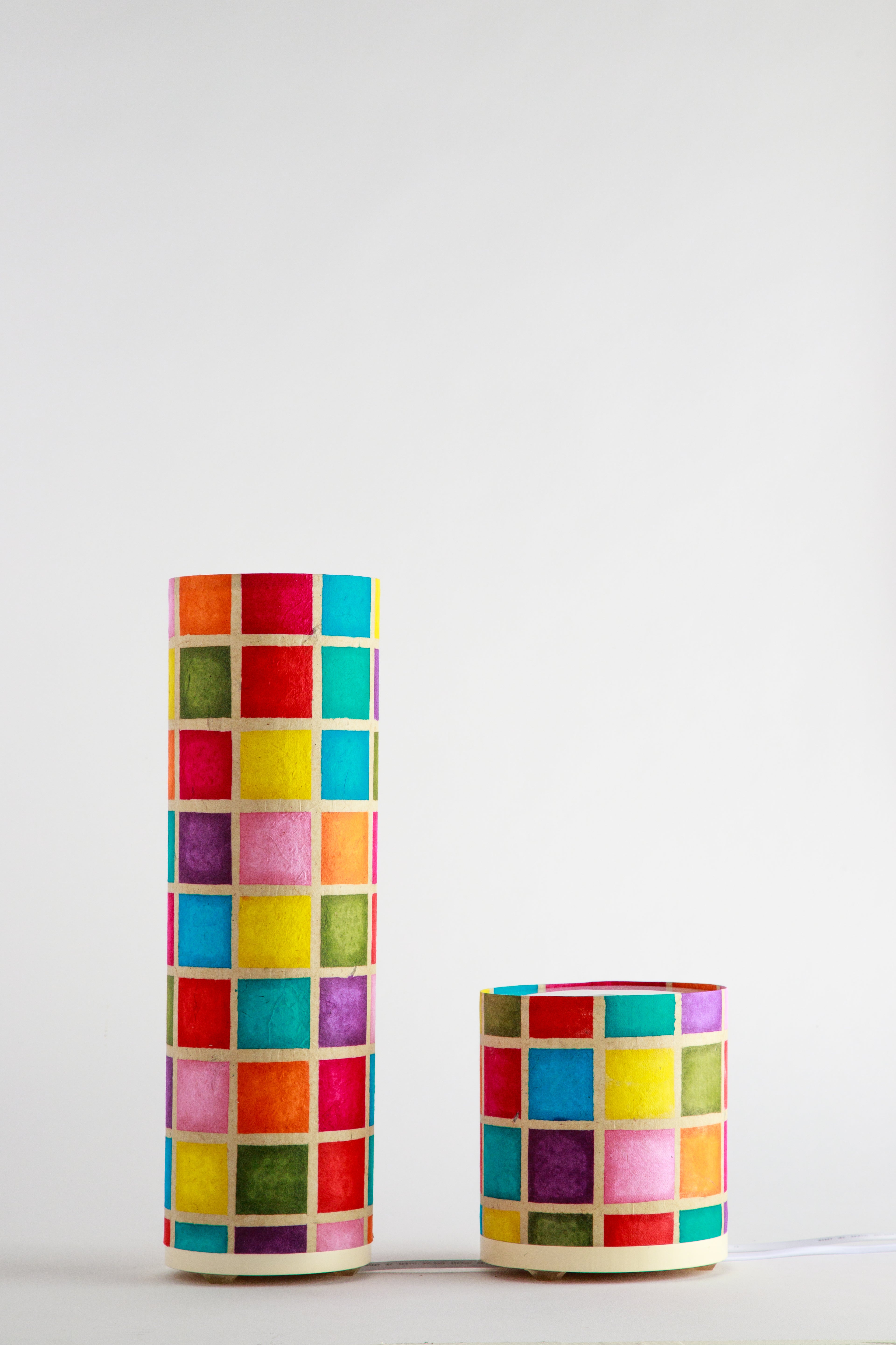 Tall and short handmade paper lamps featuring a colorful square mosaic pattern, made by artist Patricia Branstead.