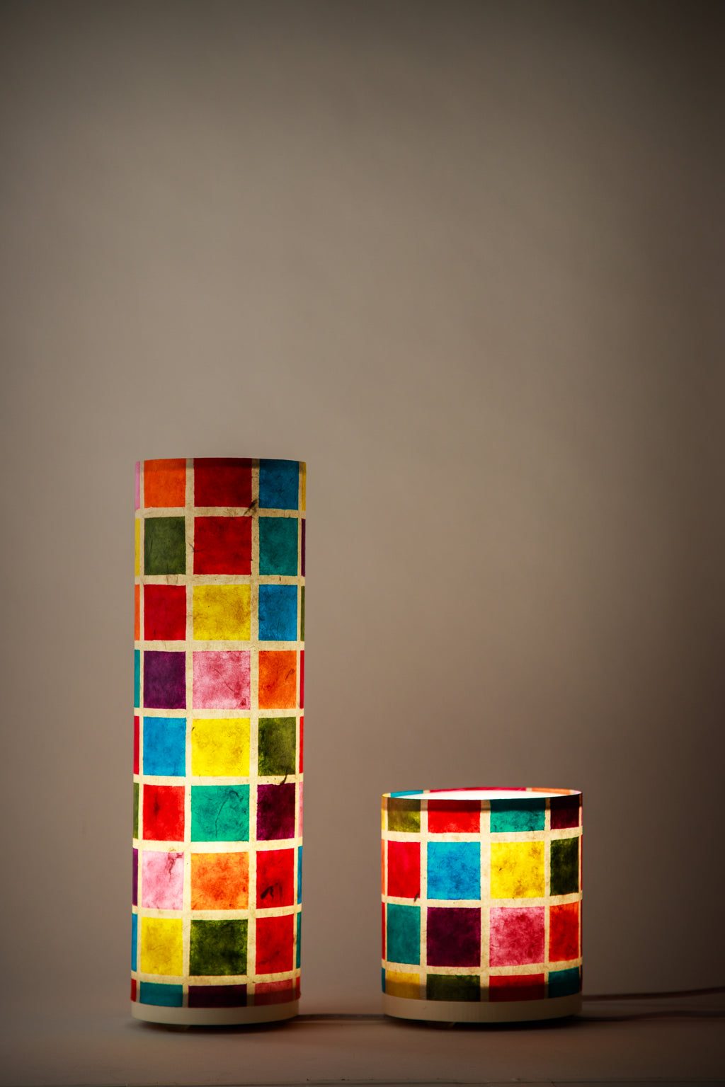 Modern cylindrical table lamp with multicolor grid design on textured paper made by artist Branstead Designs