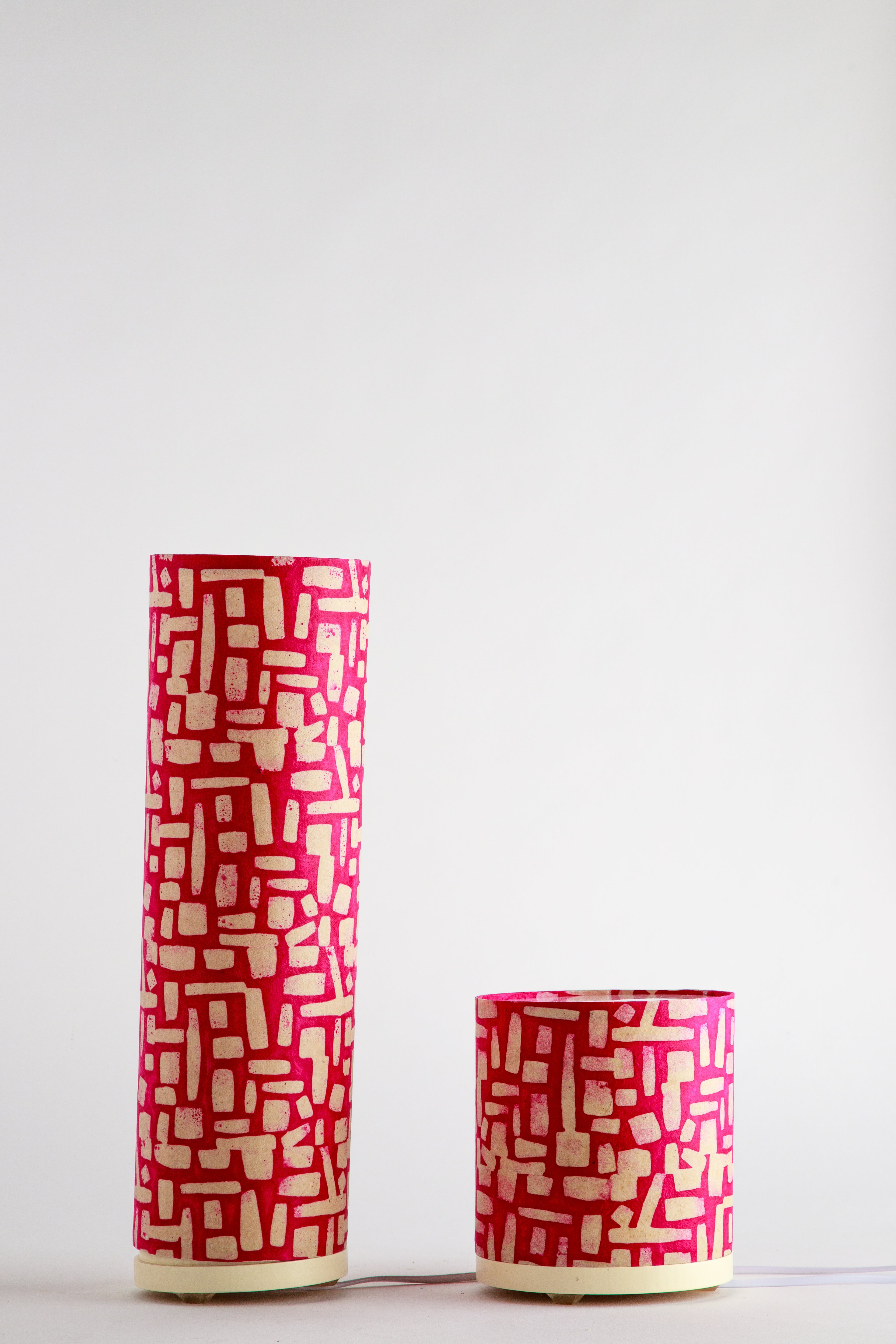Tall and short handmade paper lamps with bold red abstract geometric pattern made by artist Patricia Branstead