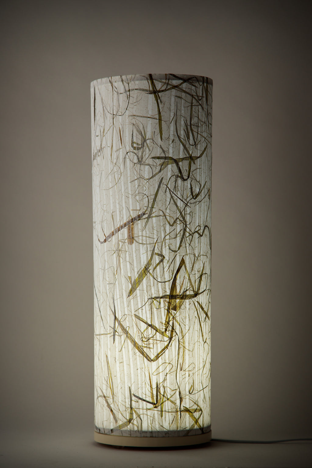 Artist-made canvas bed lamp glowing softly, revealing delicate gold and charcoal markings in a dimly lit room