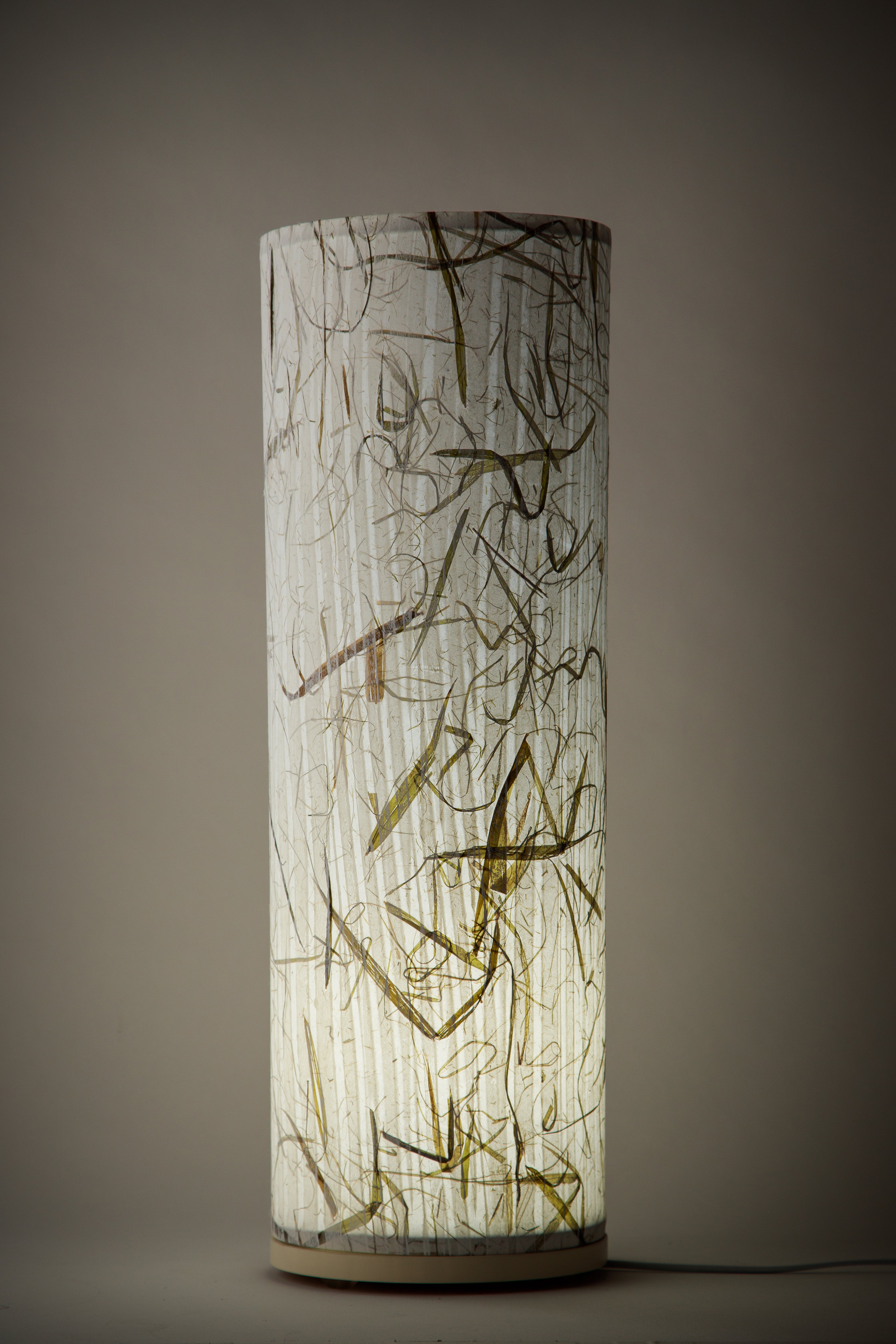 Artist-made canvas bed lamp glowing softly, revealing delicate gold and charcoal markings in a dimly lit room