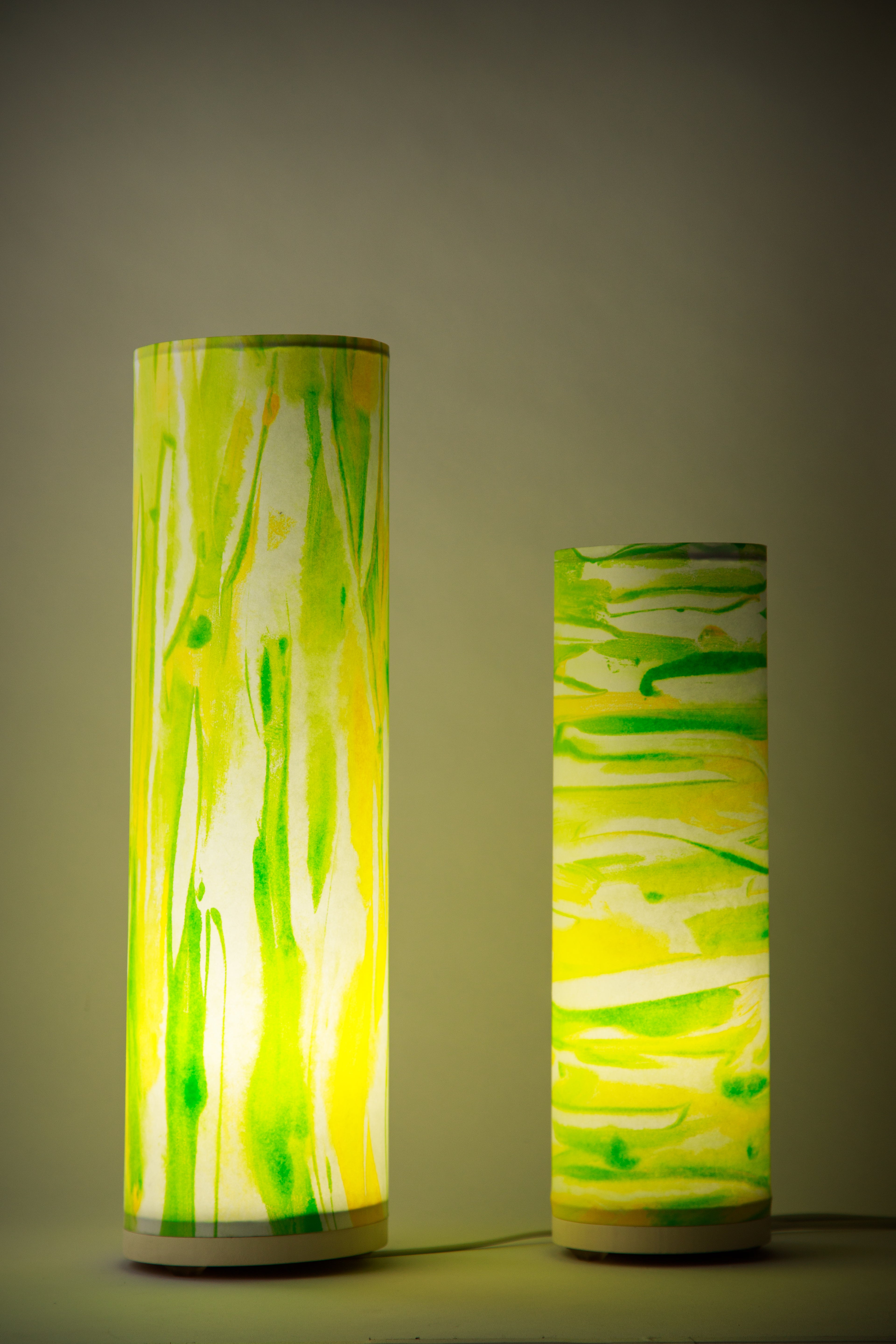 Artisan table lamp glowing warm green and yellow light in a dim room, Flux – Sunlit Spring by Patricia Branstead casting soft ambient illumination