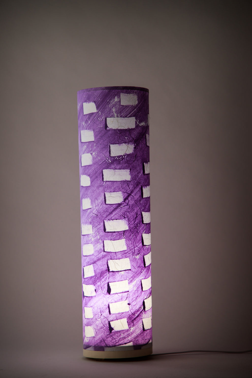 Modern abstract bedside lamp glowing softly, purple canvas illuminated in a dark room